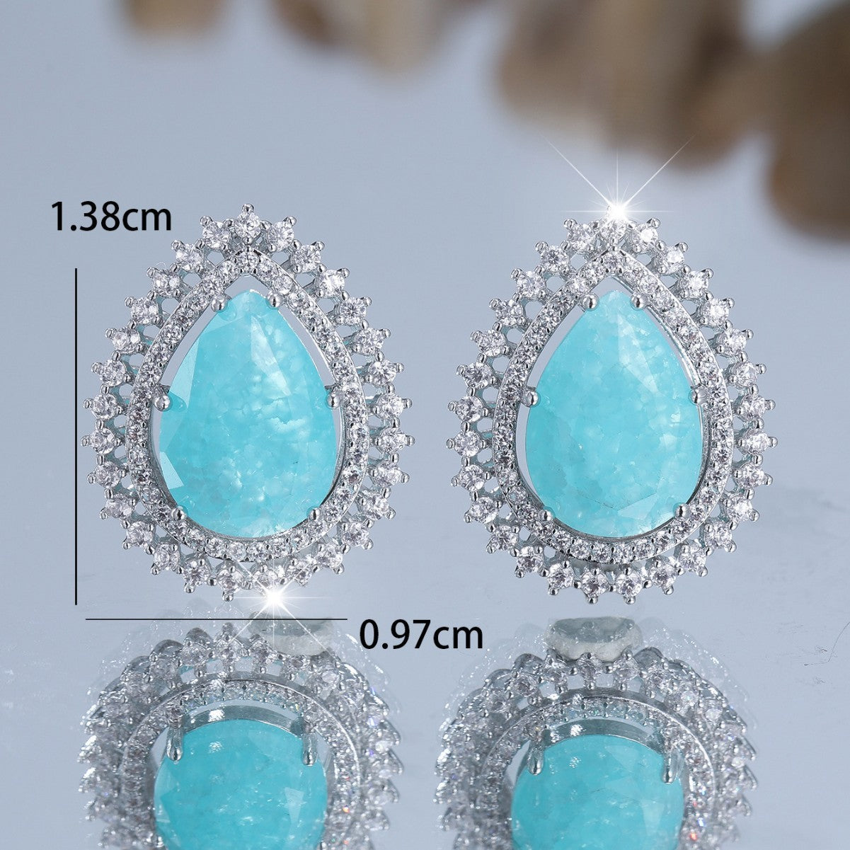 Turquoise teardrop earrings with silver accents on a light gray background