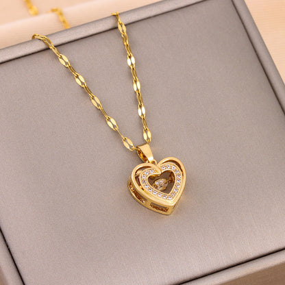 Gold heart-shaped necklace with a pendant on a gray surface