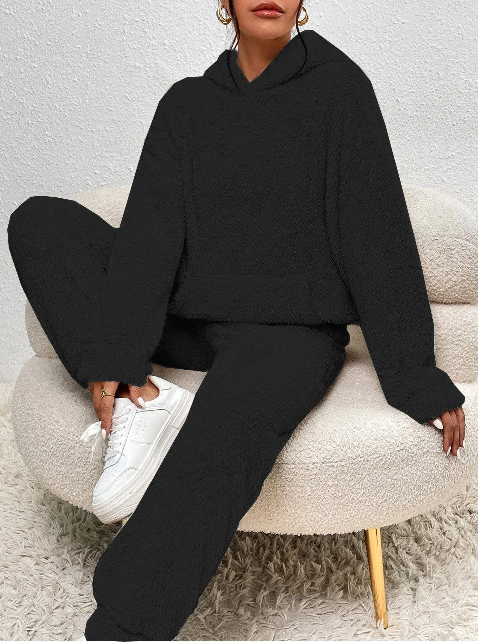 Person wearing a black hoodie and pants sitting on a beige chair.