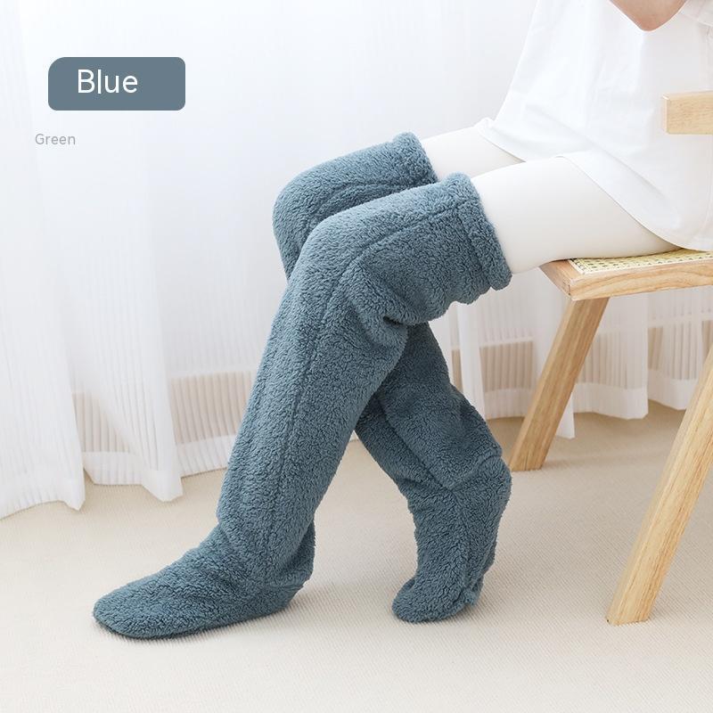 Blue fuzzy socks worn by a person sitting on a chair with a white background