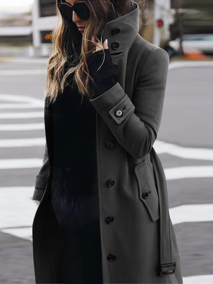 Woman wearing a long gray coat and black gloves on a city street.